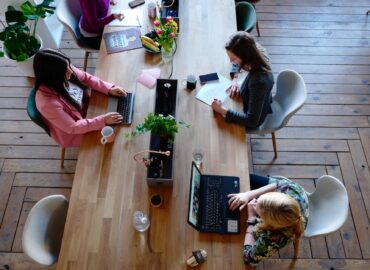 three woman sitting on white chair in front of table