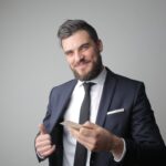 man in black suit holding a calling card